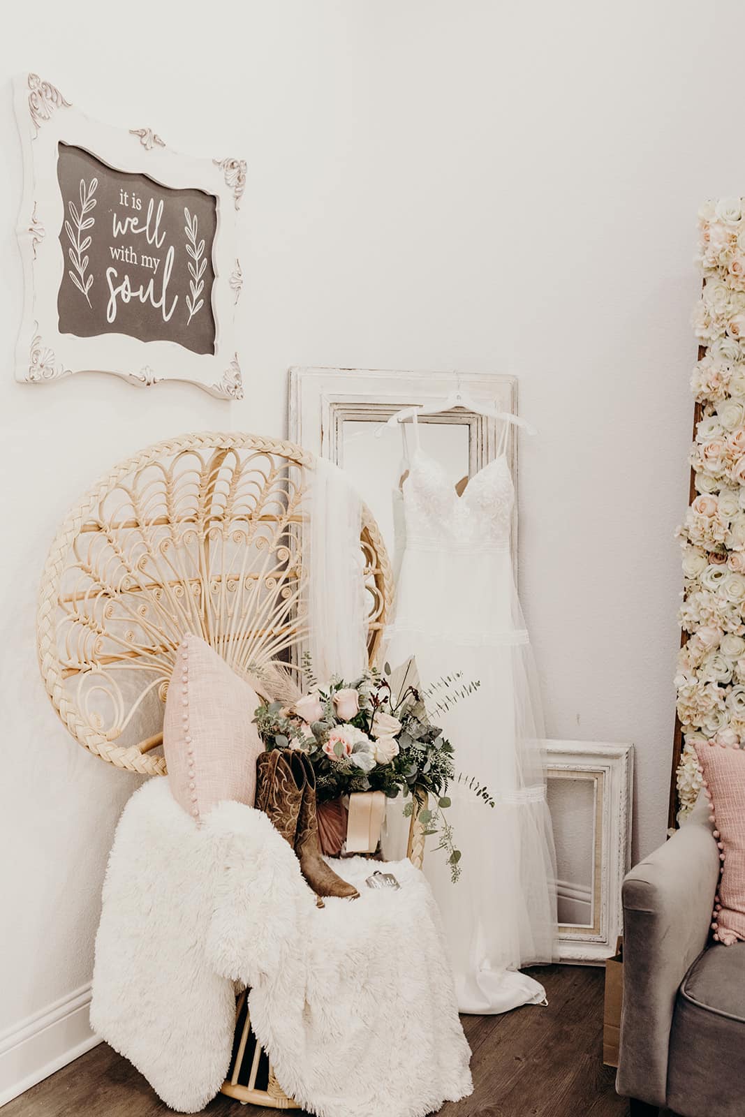 wedding gown hanging on mirror with boots and flowers