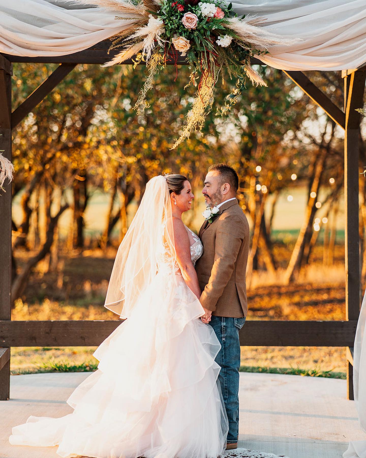 bride and groom holding hands under wooden arch