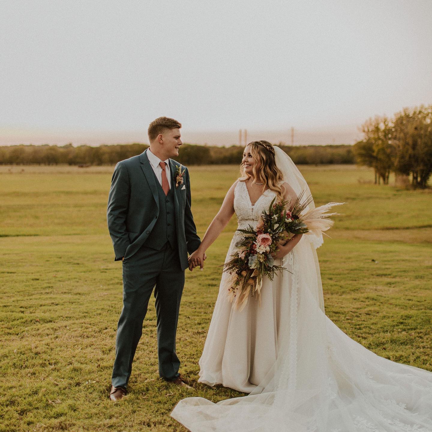 bride and groom holding hand in field