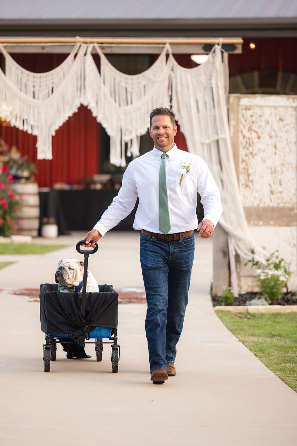 groomsman pulling dog in wagon down aisle